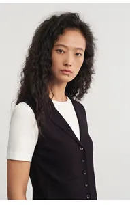 Detailansicht einer schwarzen Strickweste mit Knöpfen über einem weißen T-Shirt.
