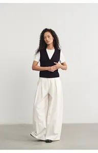 Schicke schwarze Strickweste kombiniert mit einer weißen weiten Hose für einen Herbst-Look.