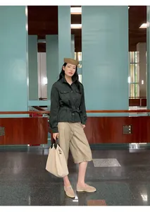 Model wearing high-waisted beige PU leather wide-leg cropped trousers in a modern lobby