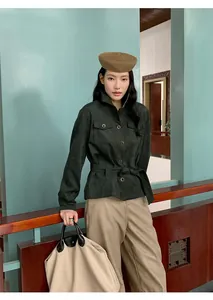 Close-up look of elegant beige wide-leg trousers and dark green utility jacket.