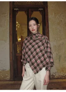Modella indossa uno scialle scozzese marrone vintage in un ambiente interno rustico