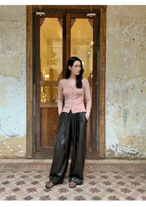 Soft pink slim-fit knit cardigan and wide-leg leather pants on model in vintage setting