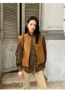 Vista dettagliata di un gilet in pelle scamosciata marrone con zip e collo alto.