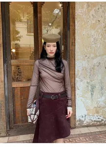Asian model wearing a retro brown asymmetric A-line skirt in a vintage outdoor setting.