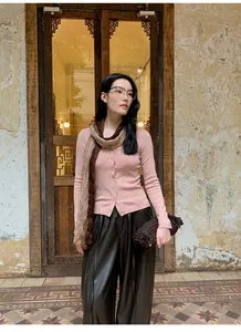 Asian model wearing a slim-fit pink knitted cardigan with a matching scarf in a vintage outdoor setting
