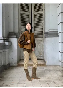 Vista intera di una modella con gilet in camoscio marrone su uno sfondo vintage