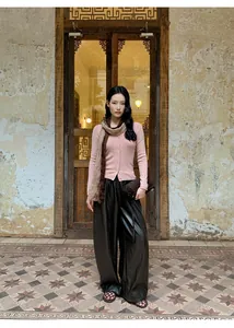 Full body view of model in pink slim-fit cardigan and black wide-leg leather trousers