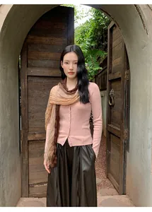 Elegant detail of soft pink knitted cardigan styled with a chic gradient brown scarf