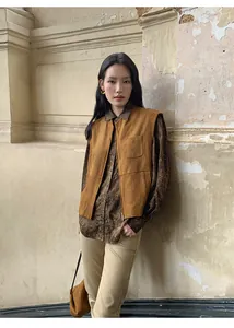 Vista dettagliata di un gilet in pelle scamosciata marrone sopra una camicia vintage per l'autunno.