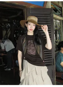 Close-up of beige asymmetric tiered skirt styled with a brown graphic T-shirt in a cafe setting