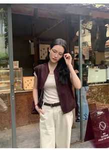 Dettaglio gilet scamosciato marrone da donna indossato in un bar in stile Maillard