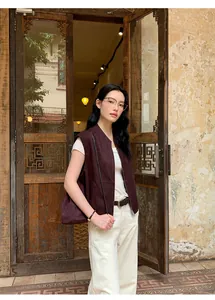 Modella asiatica che indossa un gilet di camoscio bordeaux davanti a una porta vintage.