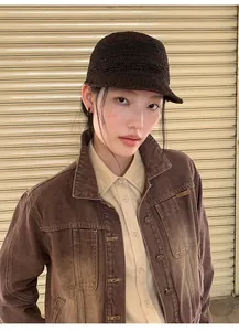 Detail view of brown gradient washed denim jacket with lapel on model in knit hat.
