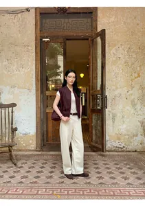 Vista intera di una donna con gilet scamosciato marrone a collo alto in un ambiente vintage