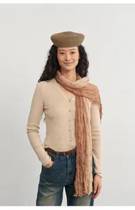 Model wearing a beige V-neck knitted cardigan with matching tan scarf and beret