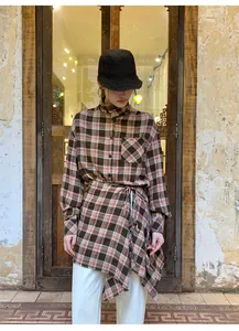 Modella con camicia a grembiule a quadri marroni retrò e cappello a secchiello nero