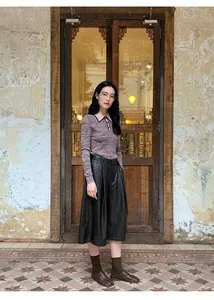 Asian model styling high-waist wide-leg black PU leather culottes in a retro rustic setting.