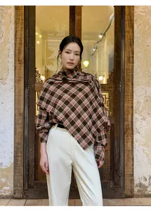 Dettaglio di una modella che indossa uno scialle vintage a quadri e pantaloni bianchi