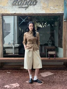 Vintage bruin corduroy werkjasje met riem voor dames, gestyled met een beige culotte en schoenen