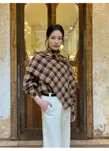 Elegante poncho scozzese vintage su modello davanti a un rustico sfondo in legno