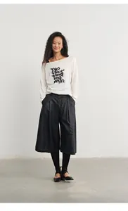 Professional full-body studio shot of woman wearing high-waist wide-leg faux leather culottes