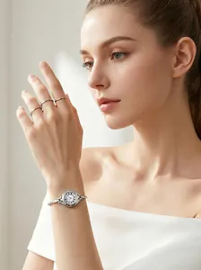 Elegant silver bracelet watch with a small round dial worn by a model in soft light.