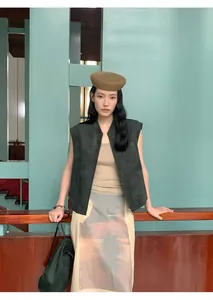 Gilet senza maniche in camoscio verde scuro abbinato a cappello e gonna in un ambiente artistico