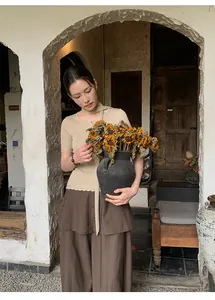 Asian model wearing a beige knit top and brown tiered culottes in a rustic archway setting