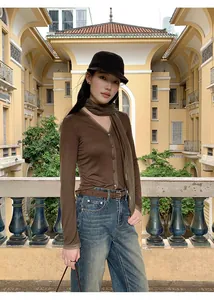 Model draagt een stijlvolle bruine gebreide top met V-hals en elegant mesh sjaaldetail