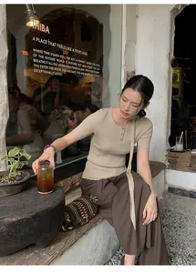Asian model wearing high waist brown wide-leg trousers in a rustic cafe setting