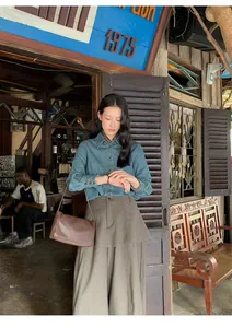 High-waist layered brown skirt-trousers styled with a denim shirt in a vintage rustic setting