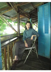 Asian model in a denim shirt and grey high-waist wide-leg skort pants in a rustic setting.