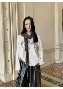 Camiseta elegante de manga larga con bordado y bufanda a juego sobre una modelo