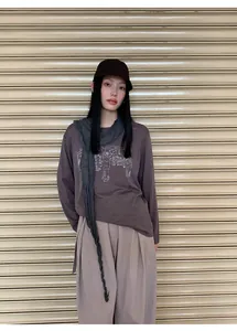Mujer con camiseta de manga larga marrón oscuro con gráfico y bufanda.