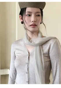 Detail van de elegante mesh sjaal op een gebreide top met lange mouwen en V-hals.