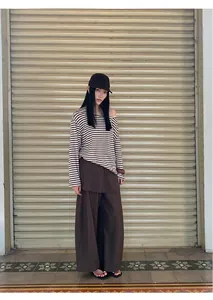 Stylish Asian model posing in a striped off-the-shoulder top and brown wide-leg trousers