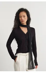 Detail van een chique zwarte gebreide top met V-hals en mesh sjaal patchwork design.