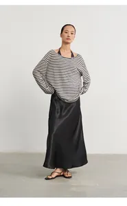 Asian fashion model posing in a striped knit cover-up sweater and black satin midi skirt