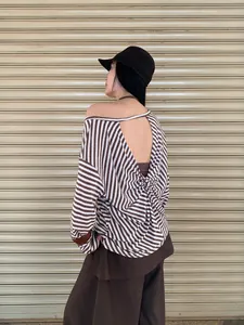 Model wearing a brown and white striped open-back two-piece cover-up set against a shutter