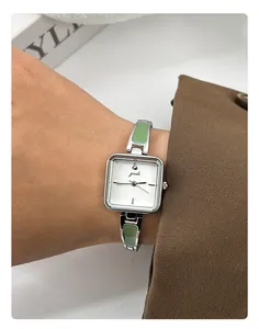Close-up of elegant square quartz watch with green enamel strap detail on wrist