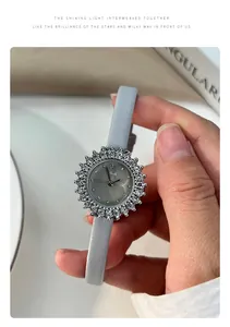 Detail shot of a vintage women's quartz watch with a sunflower rhinestone dial and grey strap.