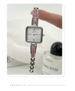Close-up detail of silver women's quartz watch with pink resin inlay held by hand