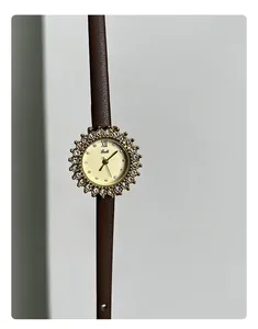 Close-up of elegant gold sunflower watch with rhinestones and brown leather strap.