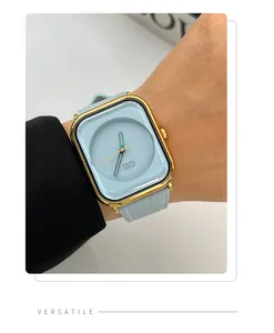 Close-up of a minimalist light blue square quartz watch with a gold-tone case on a wrist.