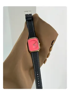 Detail shot of a women's quartz watch with coral pink dial and black leather strap.
