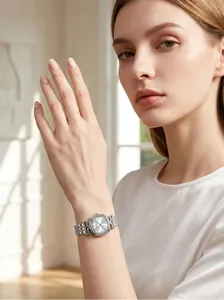 Elegante reloj de acero inoxidable plateado en la muñeca de una mujer, luz natural.