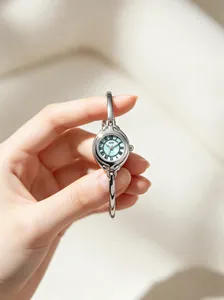Close-up of a vintage GEDI silver bracelet watch with a light blue dial held by a hand.