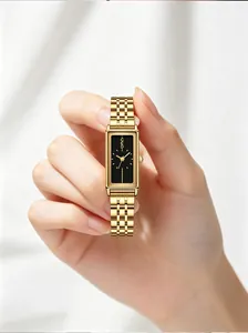 Handheld view of a GEDI gold rectangular quartz watch with a minimalist black dial.