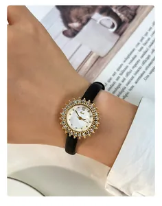Elegant ladies gold sunburst rhinestone watch with black leather strap worn on wrist