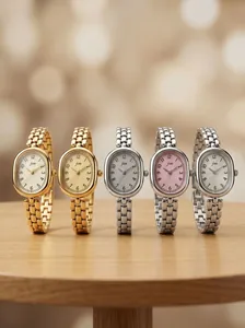 Close-up of vintage oval JW ladies quartz watches with chain straps on wooden table.